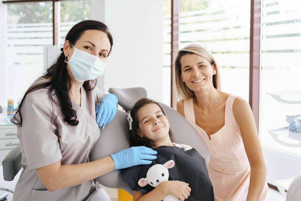 Dentist examining a child while her mother sits beside her during a dental checkup