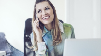 Woman sitting at her desk smiling while talking on the phone